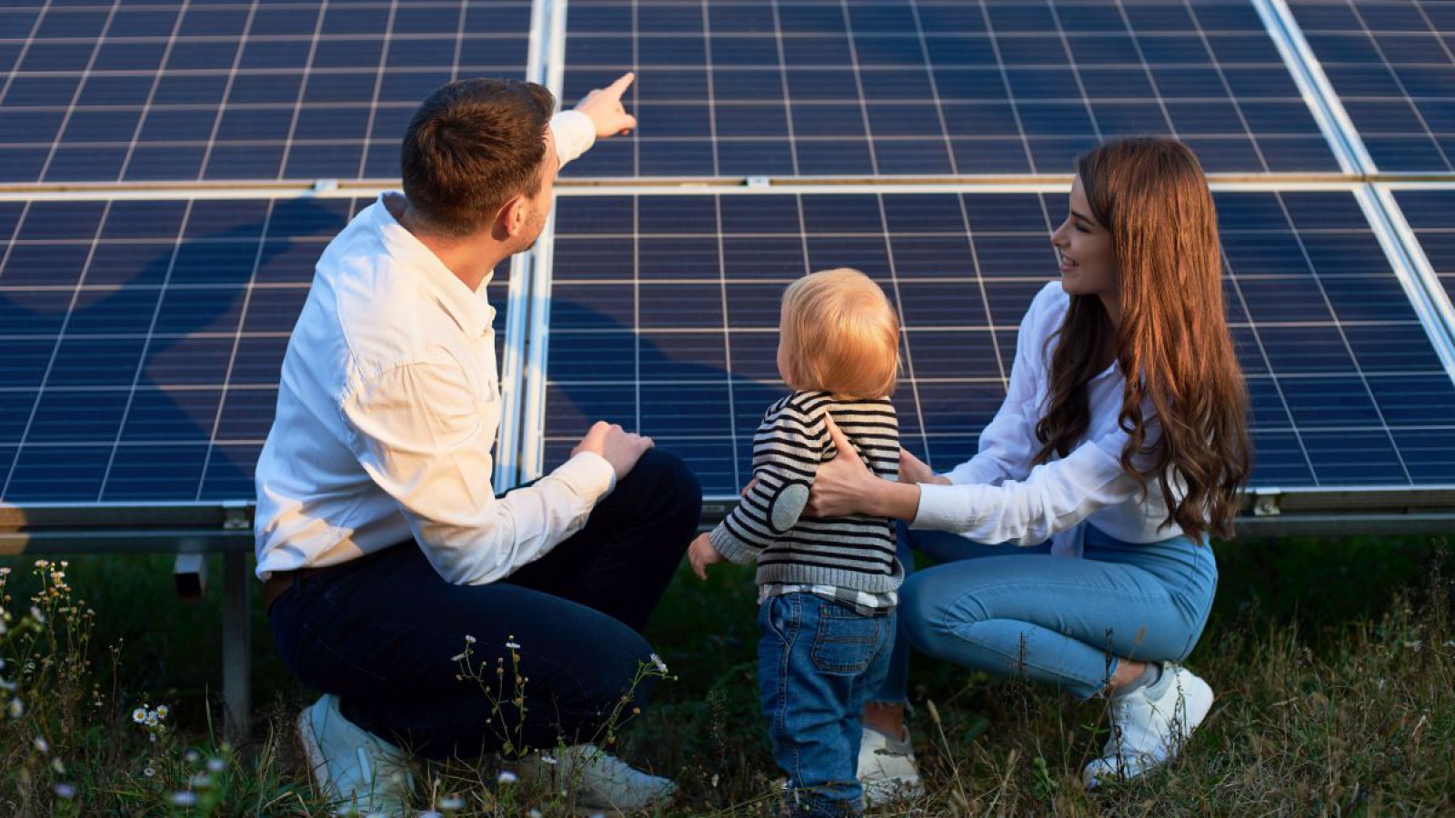 Familie sitzt vor einer Photovoltaikanlage