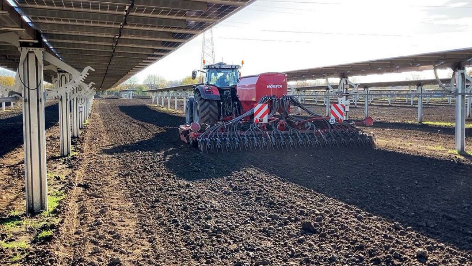 Traktor auf einem Feld mit Agri-PV-Anlage