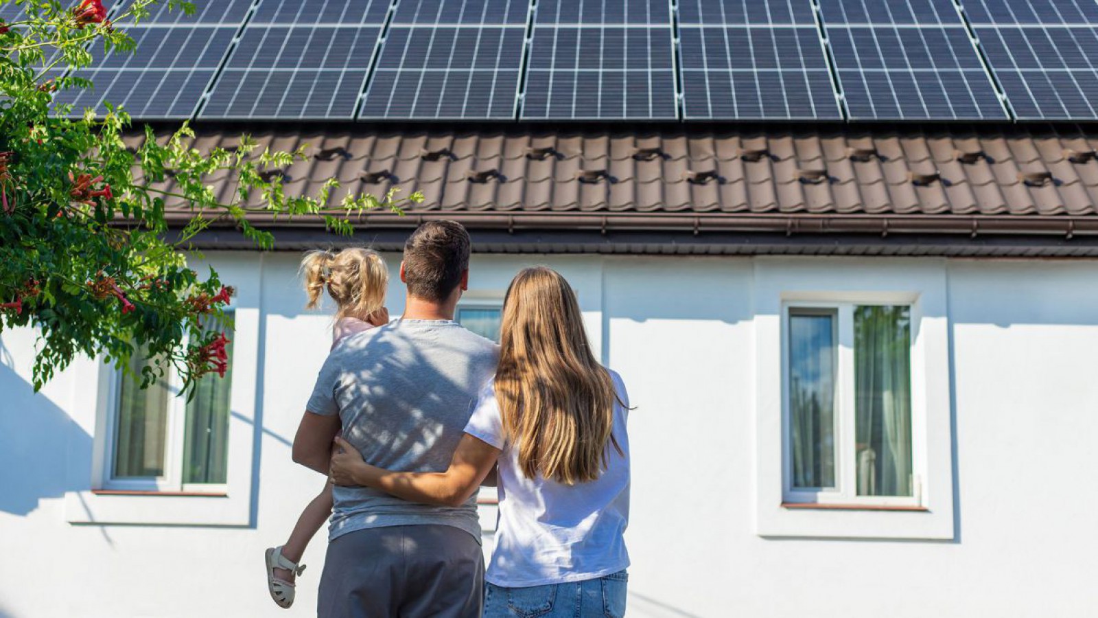 Familie vor einer PV-Anlage am Hausdach