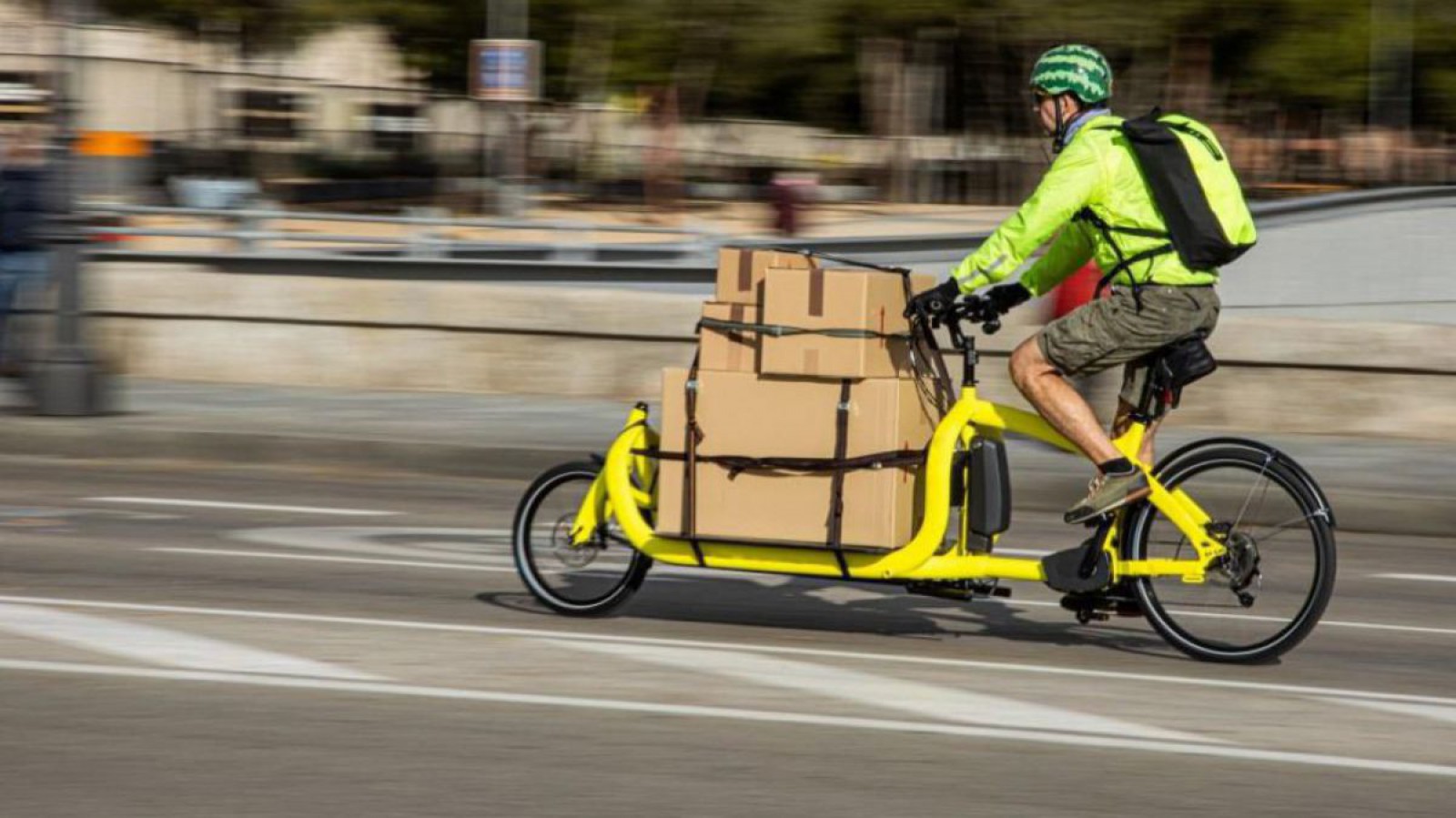 Ein Mann transportiert mit einem Lastenrad verschieden große Kartons.