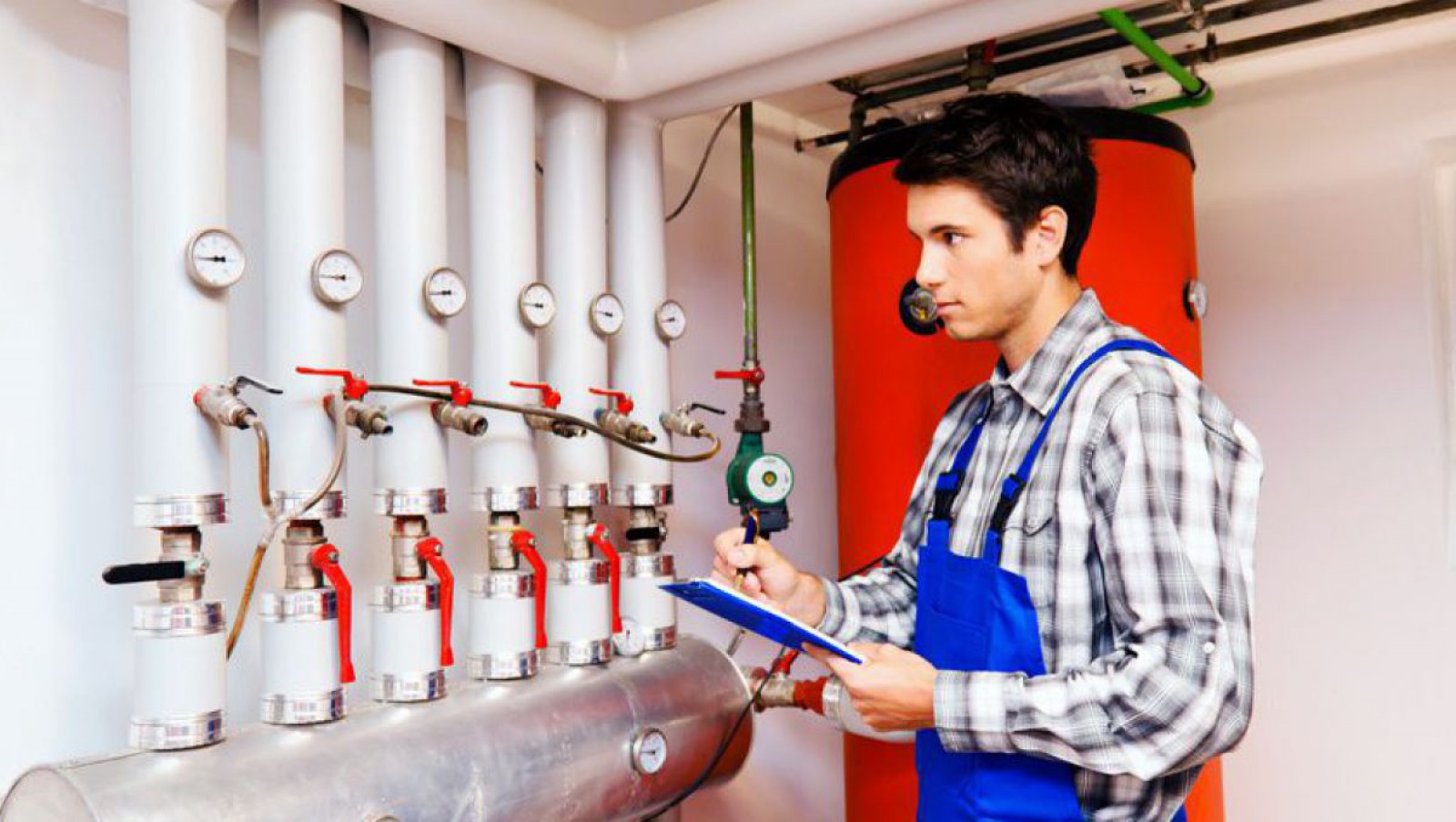 Ein Heizungstechniker, der im Heizraum einen hydraulischen Abgleich der Heizung vornimmt.