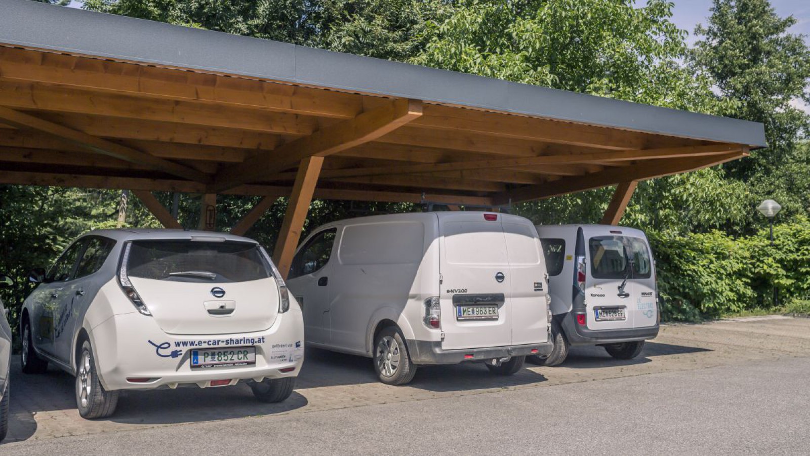 Drei Elektroautos unter einem Carport