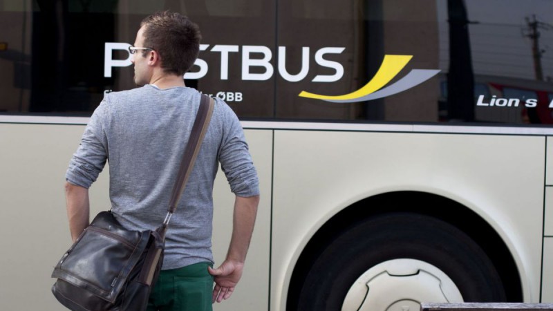 Ein Mann steht vor einem Postbus