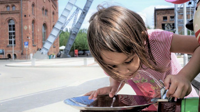 Mädchen trinkt Wasser aus öffentlichem Trinkbrunnen