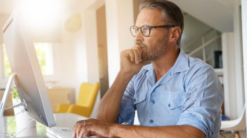 Mann arbeitet daheim am Laptop